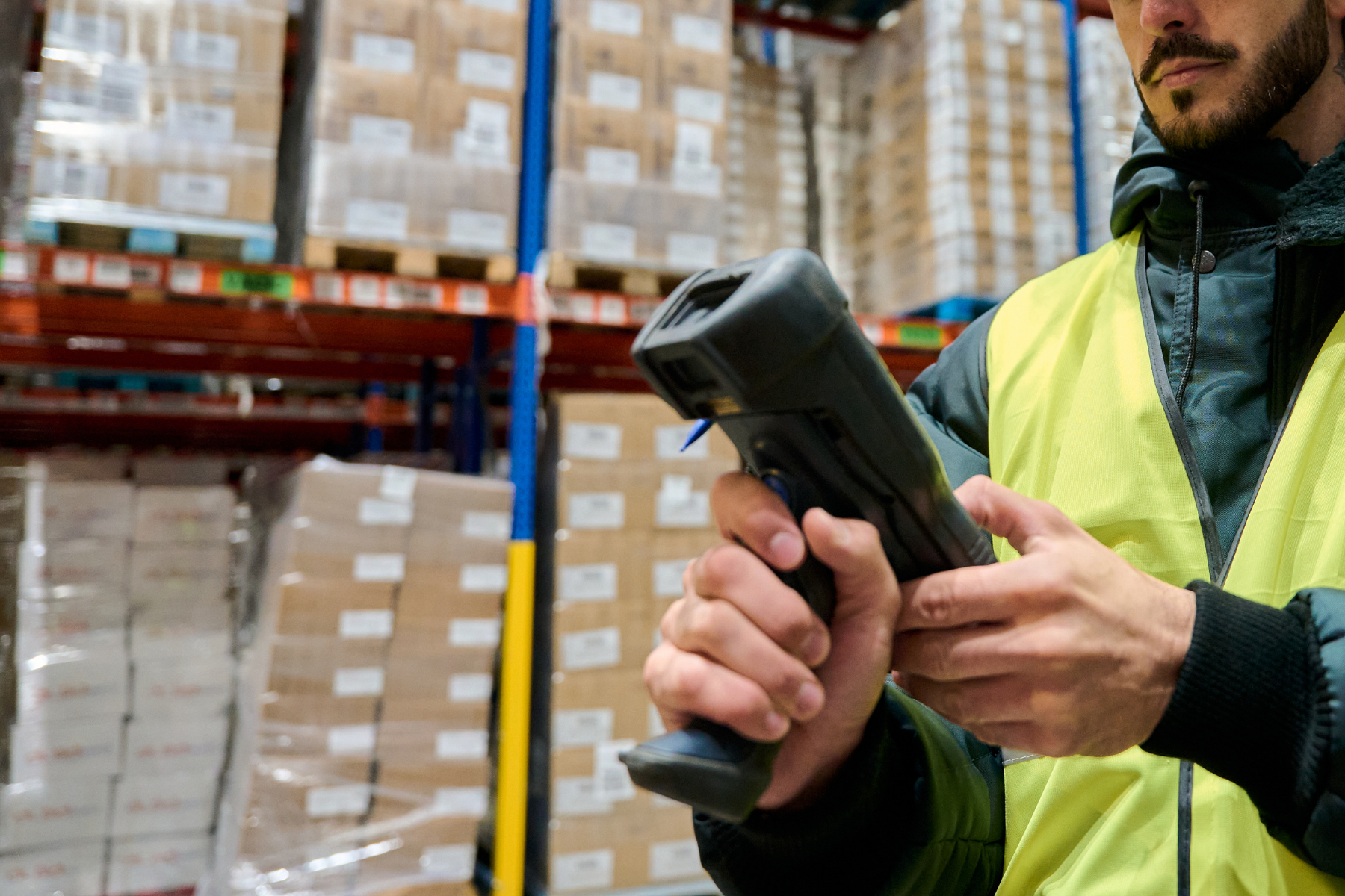 Retail Warehousing Logistics Management Systems - Scanning device being operated by a warehouse worker Infront of stock racking
